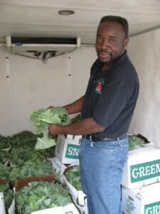 Farmer Glyen Holmes displays collard greens from his farm that will be served as one of the vegetables for this month's featured Harvest of the Month. Oxford school students will be able to enjoy collard greens, tomatoes and Southern peas as part of tomorrow's lunch menu at all schools. 