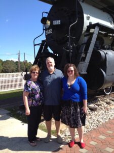 Gerri, Mike and Amelia Camurati in front of an antique steam engine in McComb.