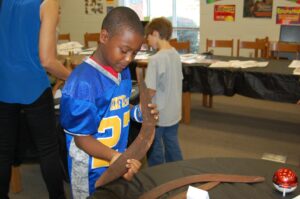 OIS student Baylor Savage checks out a boomerang on display in the OIS INSIGHTS Program Family History Museum.