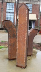 A sculpture that is part of the Yokna Sculpture Trail stands outside of the front entrance of the Powerhouse, YAC's headquarters