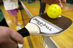 Pickleball is played with a modified wooden paddle and a plastic whiffle ball which slows down the pace of the activity resulting in long rallies.