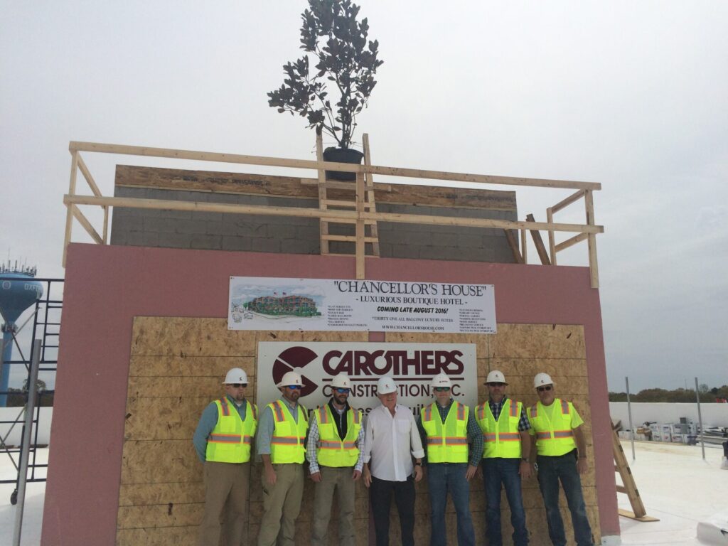 The Chancellor's House construction crew poses with the magnolia tree in completion of the traditional tree-topping ceremony. 