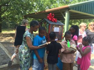 Margaret Gipson joins the children as they look at the books in the Little Free Library.
