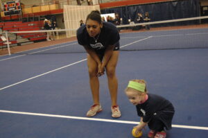 Sophomore Bri Payne teaches the 5-year-old group how to pass back and forth while playing softball.