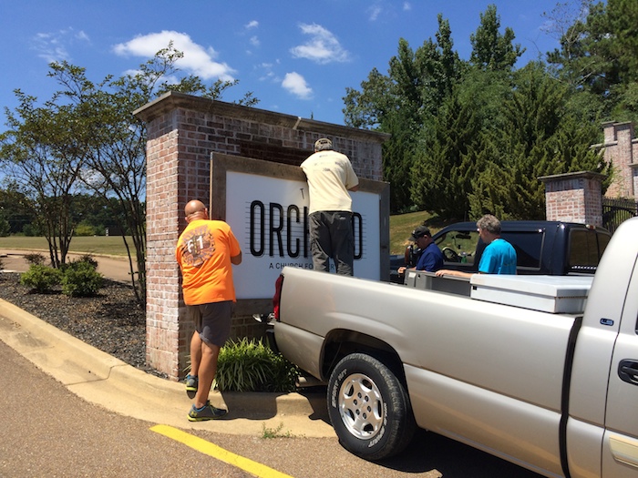 Church members help install the new sign in front of the new church.